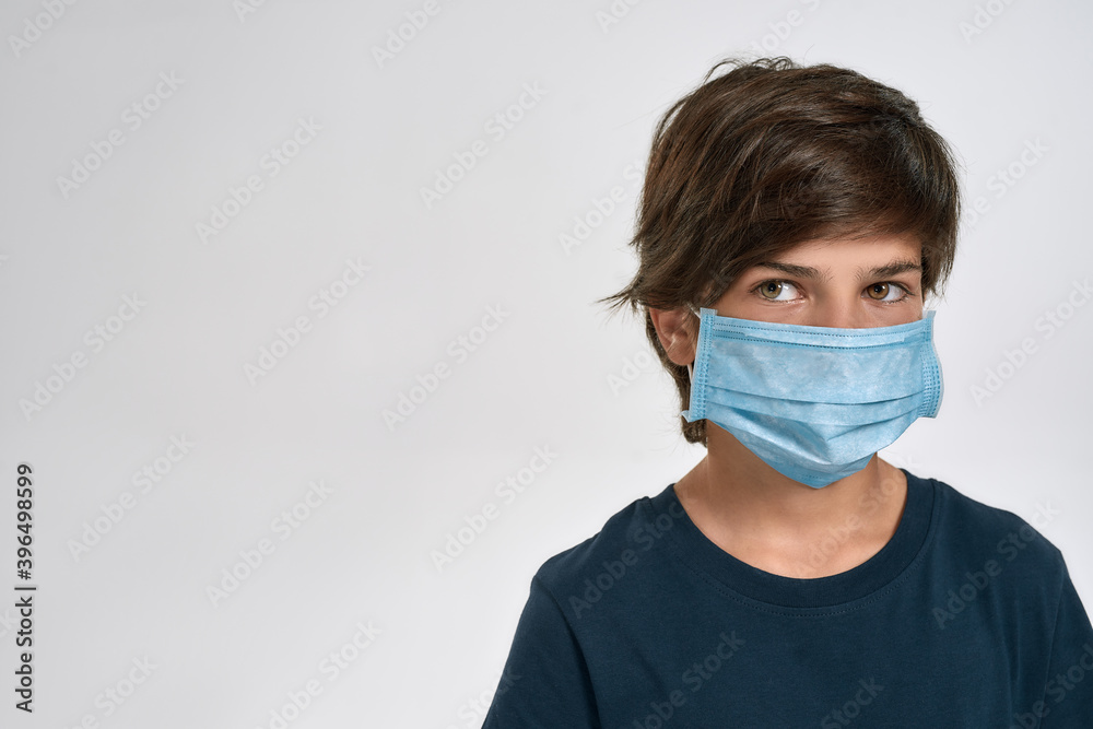 Portrait of little sportive boy child in sportswear wearing medical mask, looking aside, standing isolated over white background Portrait of little sportive boy child in sportswear wearing medical mask, looking aside, standing isolated over white background