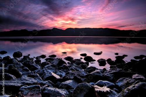 ドラマチックな空を湖面に反射するカルデラ湖。湖岸からの夕暮れの風景。
