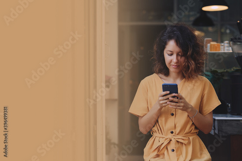 Obraz na płótnie Young woman wearing yellow dress using her smart phone in a coffee shop terrace. copy space w salonie