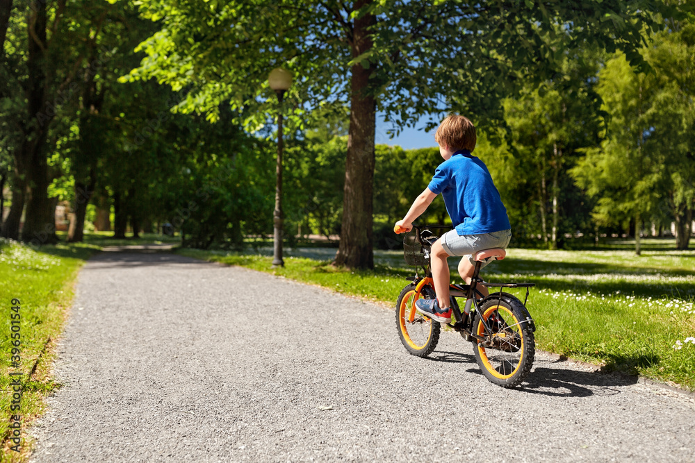 childhood, leisure and people - little boy riding bicycle at summer park childhood, leisure and people - little boy riding bicycle at summer park