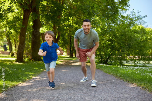 family, fatherhood and people concept - happy father with little son compete in running at summer park