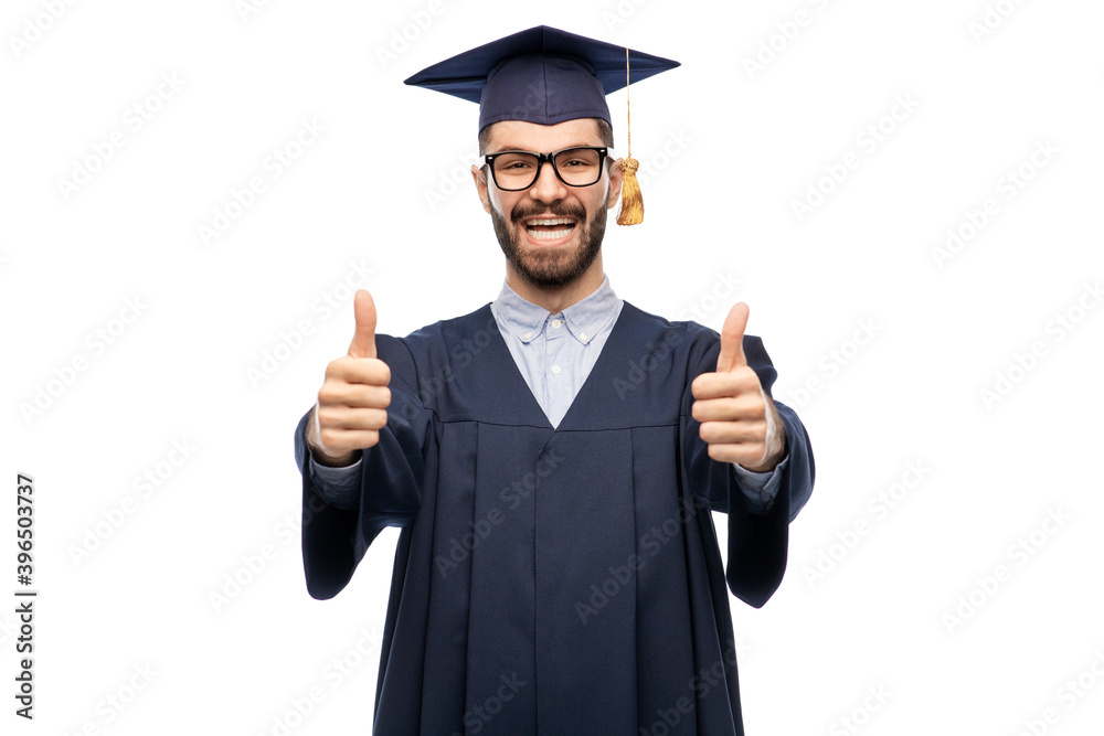education, graduation and people concept - happy smiling male graduate student in mortar board and bachelor gown showing thumbs up over grey background education, graduation and people concept - happy smiling male graduate student in mortar board and bachelor gown showing thumbs up over grey background