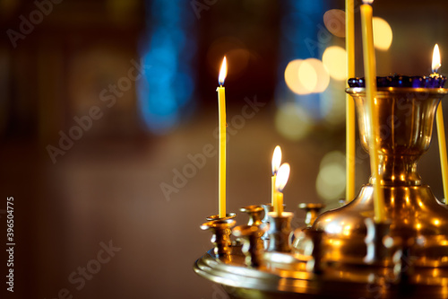 Many yellow candles stand in the old church. Christianity. Burning candle. Macro effect photo. Close-up.