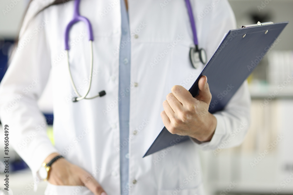 Doctor in white coat holding clipboard with documents in clinic Doctor in white coat holding clipboard with documents in clinic