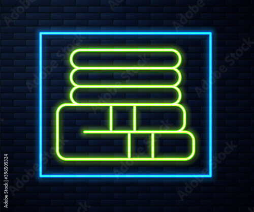 Glowing neon line Towel stack icon isolated on brick wall background. Vector.