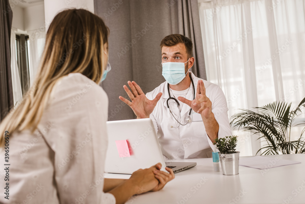 Doctor communicating with a patient while wearing protective face mask during medical appointment.