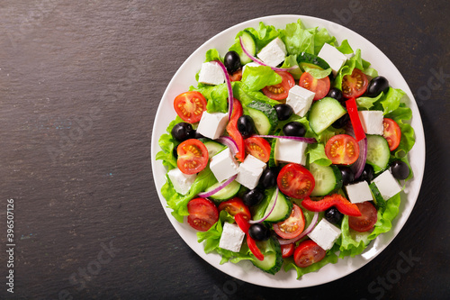 Plate of fresh salad with vegetables, feta cheese and olives. Greek salad. Top view