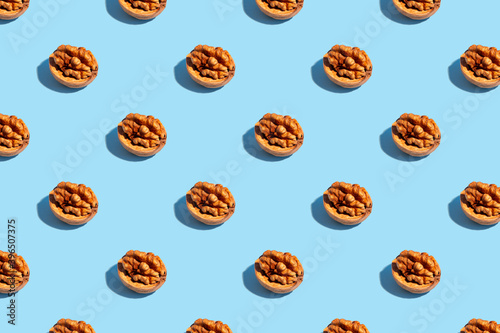 Seamless regular pattern with walnuts on a light blue background. Hard light. The concept of vegetarianism and proper nutrition.