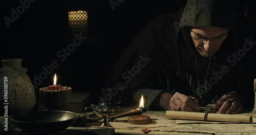 Ancient scribe writing with quill pen on old parchment photo