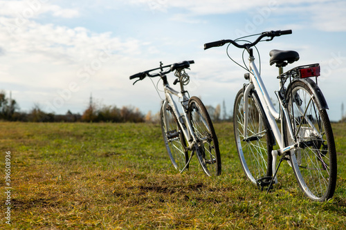two bicycles stand in a field on a dirt road against the background of mountains cycling in the open air