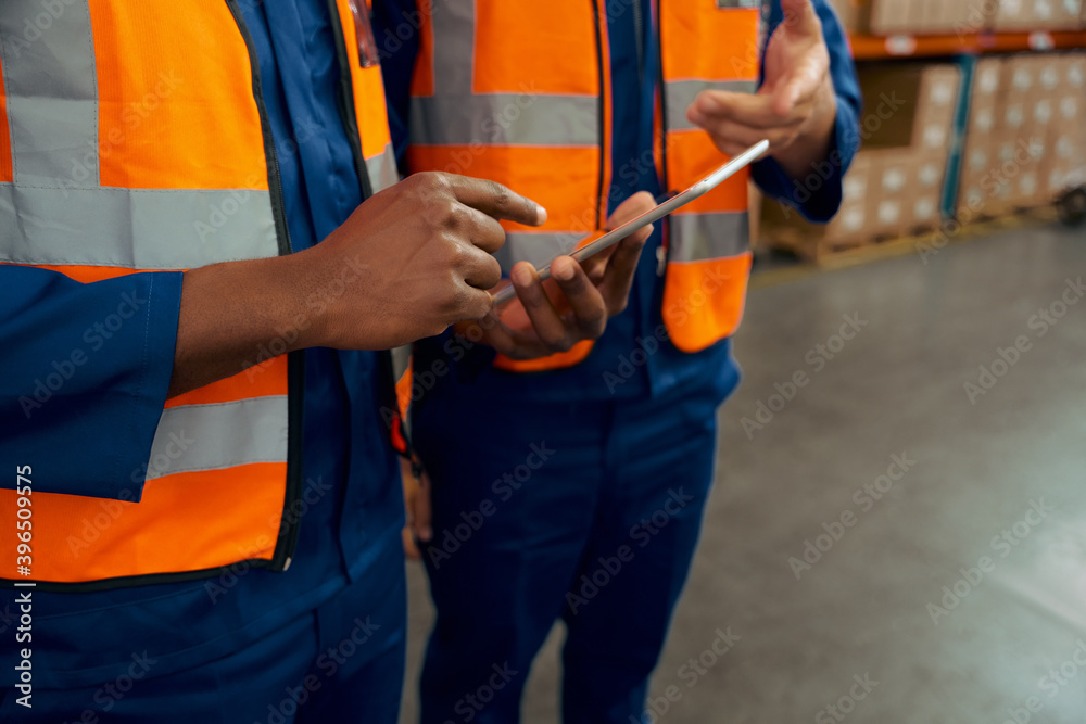 Mid section of two male employees holding digital tablet in manufacturing industry