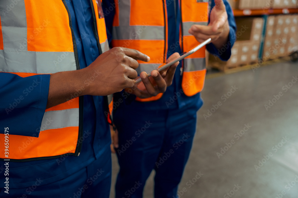Mid section of two male employees holding digital tablet in manufacturing industry Mid section of two male employees holding digital tablet in manufacturing industry
