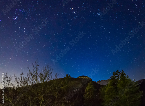 Dolomites by nightSky with stars on a winter night in val di fassa. Dolomites, forest and night lights of Pozza di Fassa