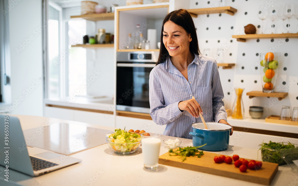 Happy beautiful woman learning to cook with online course at home