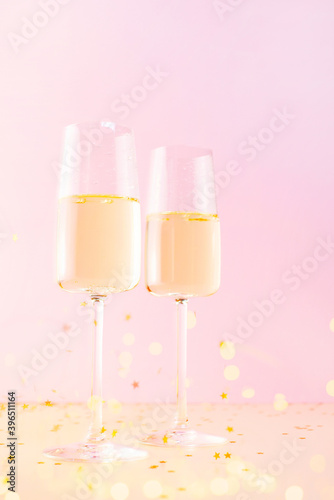 Two glasses of champagne or wine on the pink background, creative festive composition