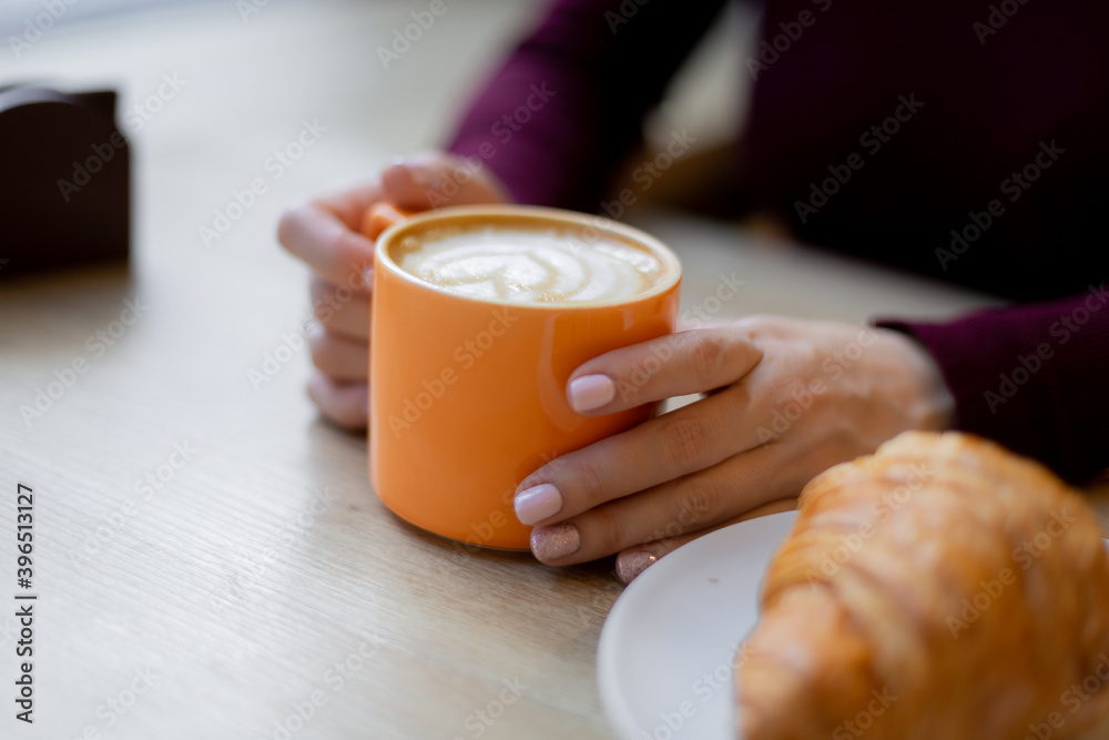 A girl has a croissant for Breakfast in a cafe