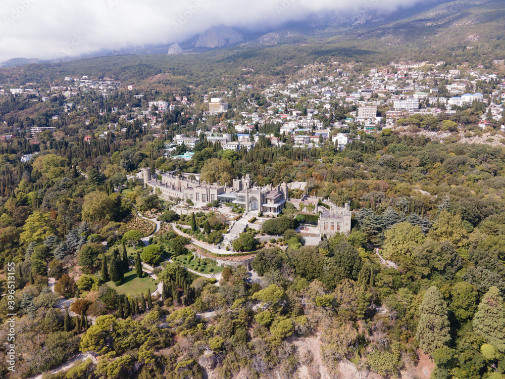 Aerial drone photo of Vorontsov palace, huge green famous garden against the mountains hidden in fog in sunny day, sightseeing in the Crimea