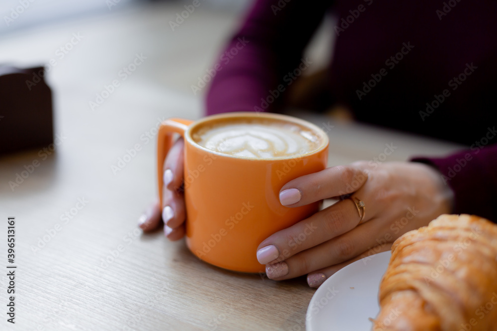 A girl has a croissant for Breakfast in a cafe