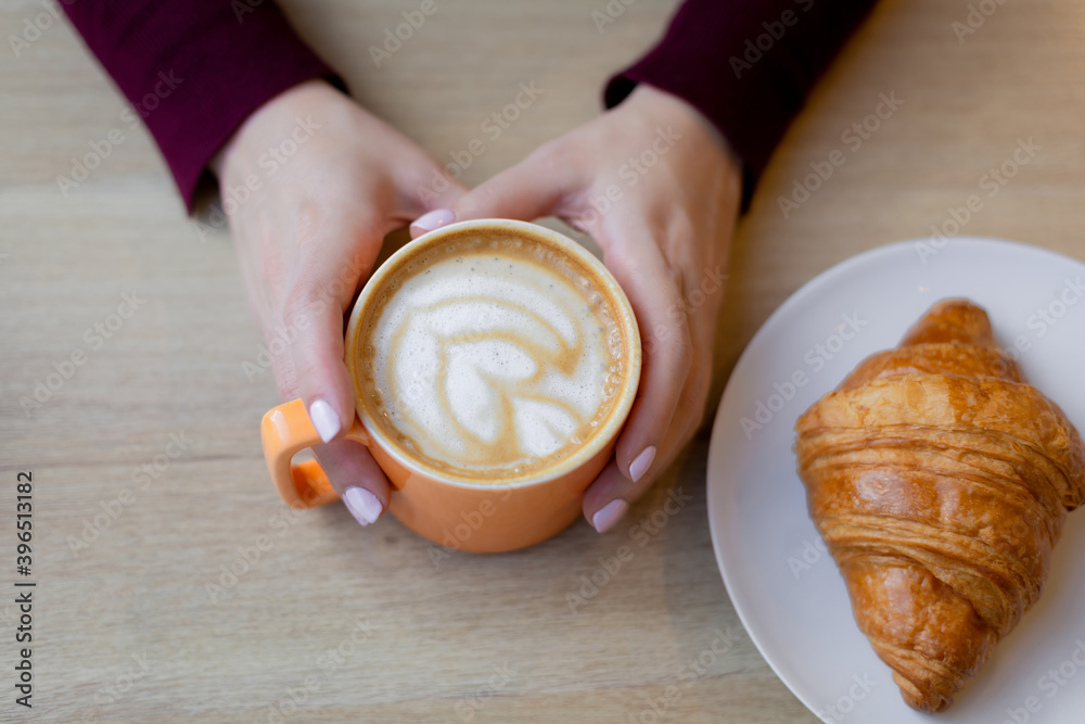 A girl has a croissant for Breakfast in a cafe