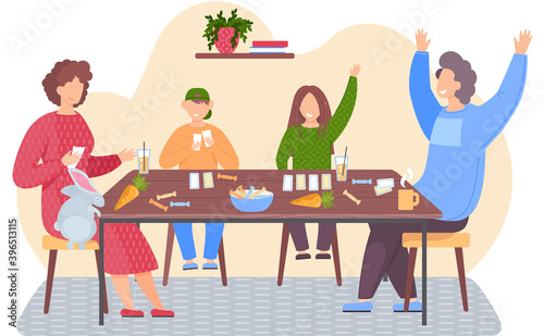 Parents and children spending time together. Kids joyfully raise hands. People are playing board game. Family sitting in an apartment with cards in their hands. Rabbit climbs on the table for a carrot