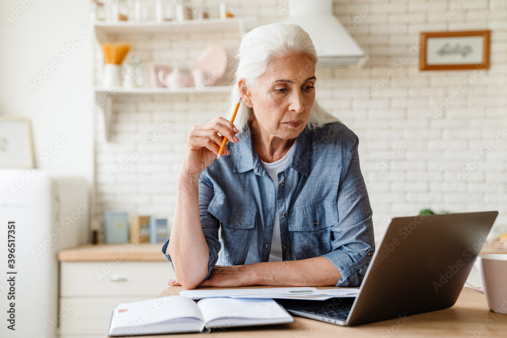 Pensive mature middle aged woman using laptop Pensive mature middle aged woman using laptop
