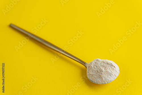 Sunflower lecithin in a spoon on a yellow background.