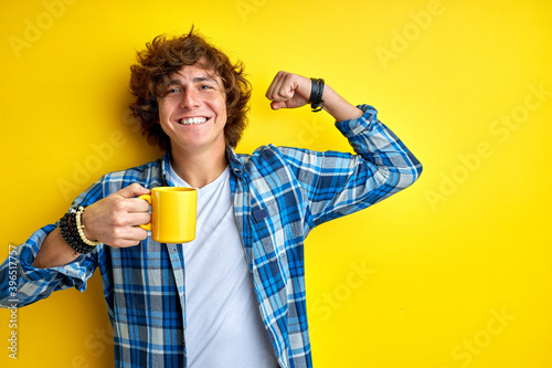 curly man with cup, feel happy ang enegry in the morning, isolated on colourful background in studio photo