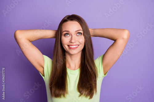 Photo portrait of relaxed girl with hands behind head looking up isolated on vivid purple colored background