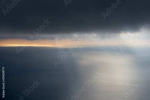 ciel nuageux où percent des rayons de soleil au-dessus de la mer  © Christophe