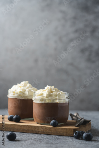 Chocolate mousse in glass jar with whipped cream. Sweet dessert close-up view