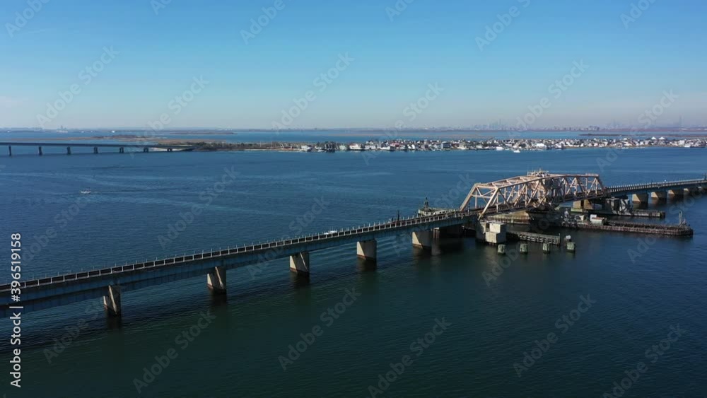 A high angle shot over elevated train tracks crossing a bay in Queens, NY. The camera truck left & pan right over the water focused on the swing bridge. The sun is shining & it is a beautiful day. A high angle shot over elevated train tracks crossing a bay in Queens, NY. The camera truck left & pan right over the water focused on the swing bridge. The sun is shining & it is a beautiful day.