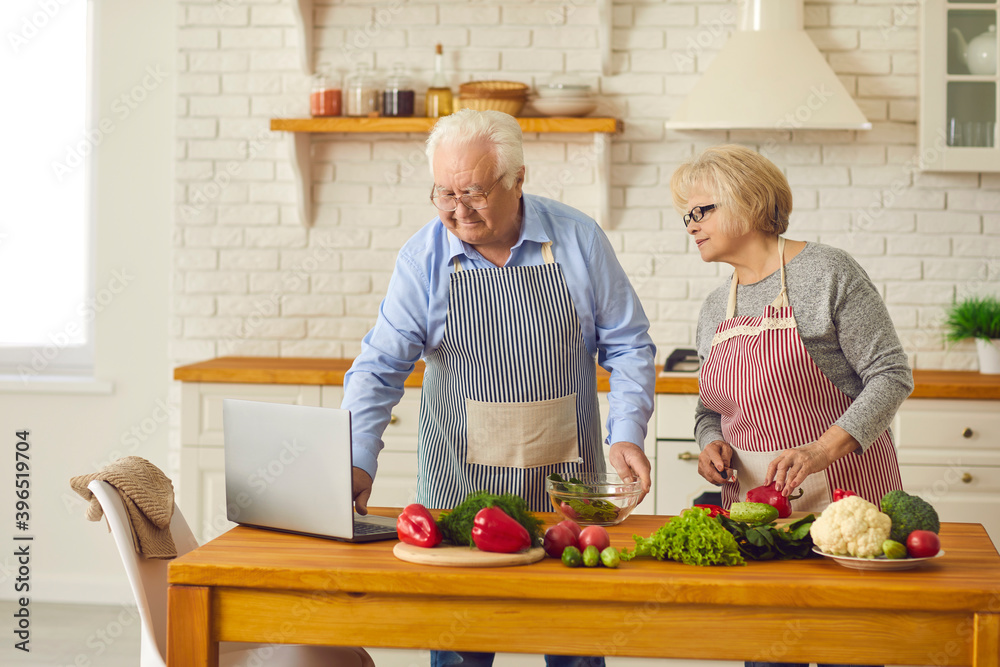 Happy senior couple watching video recipe and making healthy vegetarian meal at home Happy senior couple watching video recipe and making healthy vegetarian meal at home