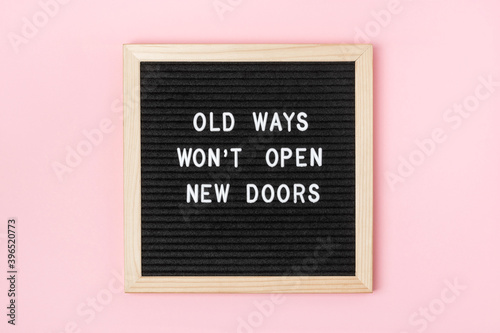 Old Ways Won't Open New Doors. Motivational quote on black letter board on pink background. Concept inspirational quote of the day. Greeting card, postcard