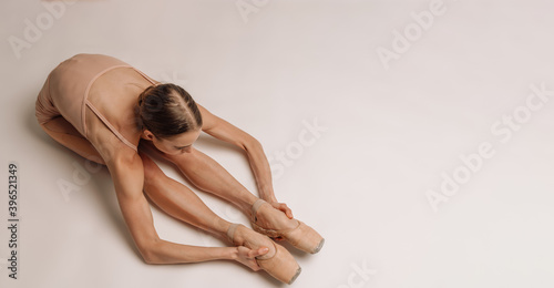Beautiful young focused ballerina stretching her body