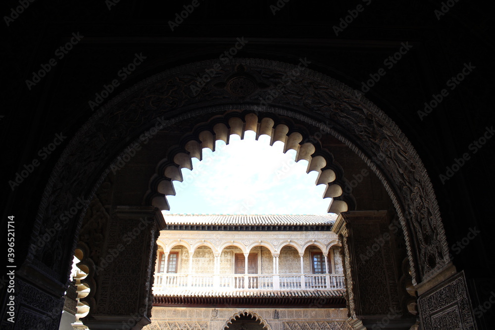 Arco de un patio en Sevilla de arquitectura árabe-andaluza con el palacio árabe al fondo