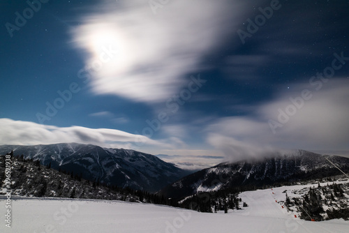 Fresh groomed snow on ski slope at ski resort at cloudy night. Snow groomer tracks on a mountain ski piste.