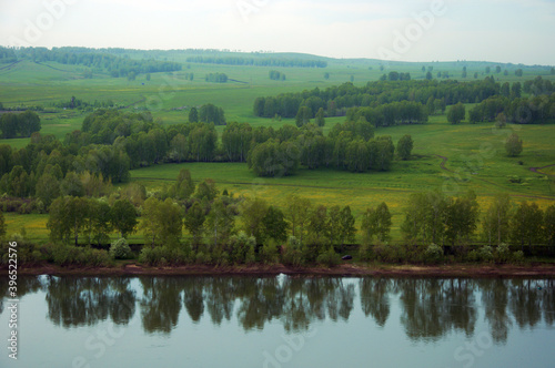 Summer wide-angle panorama of the river, the picturesque shore and the cloudy sky. Wide calm river distance with gentle green banks. Typical landscape of central Russia. Siberia. © Anna