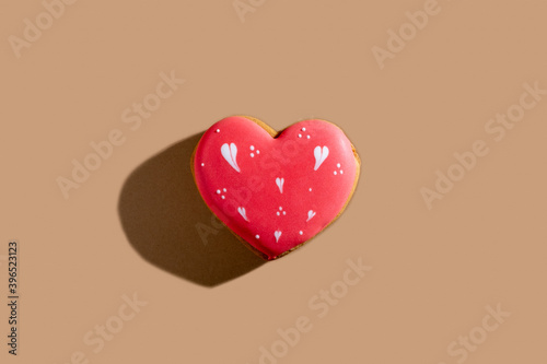 Happy valentines day. Love pastry. Festive decorated bakery. Homemade red white icing gingerbread heart cookie isolated on beige pastel.