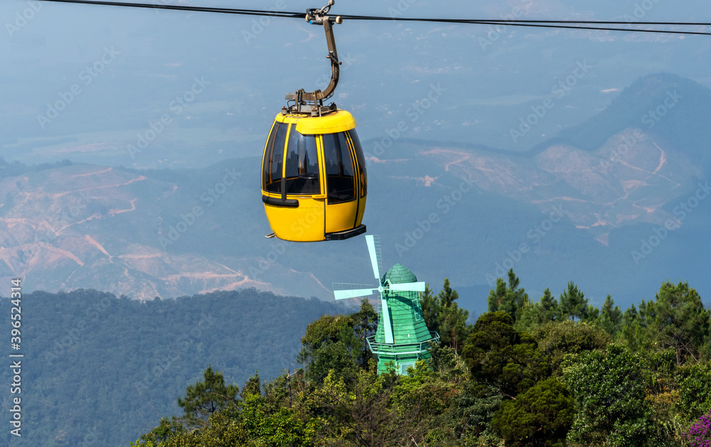 Cable car over old windmill and green forest