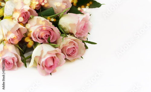 Pink rose flowers bouquet and yellow holiday lights on white background