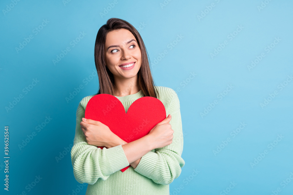 Photo of pretty young lady embrace red paper heart look up empty space wear green pullover isolated blue color background