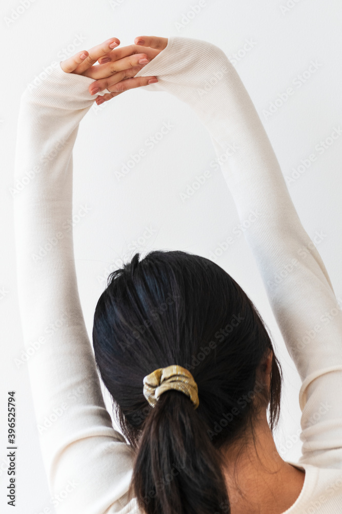 Fototapeta premium Rear view of a young woman stretching her arms