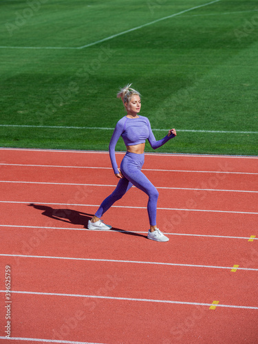 sexy fitness woman in sportswear. athletic lady warming up on stadium running track. female athlete do sport workout. trainer or coach training. perfect body shape. healthy and sporty