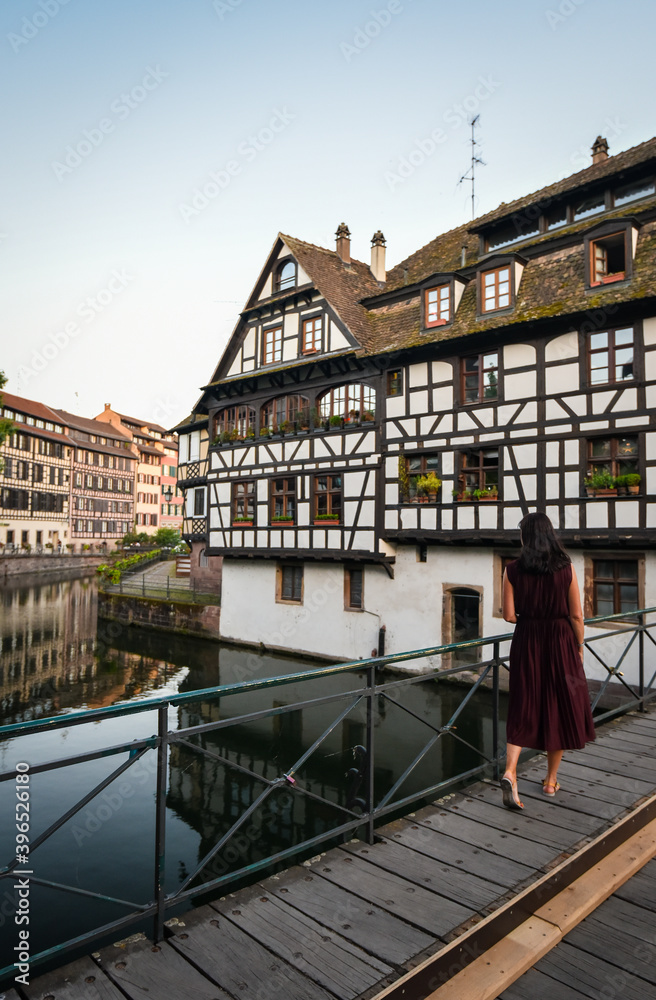 Tourist walking in old town water canal of Strasbourg, Alsace, France. Traditional half timbered houses of Petite France at dawn