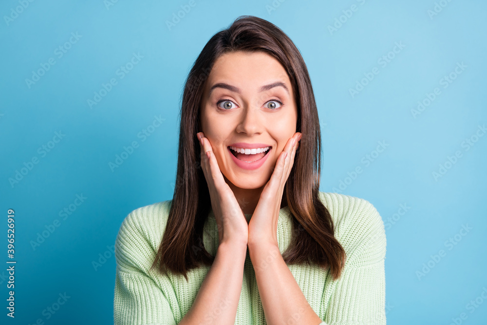 Photo of cute young lady arms cheeks amazed expression wear green pullover isolated blue color background