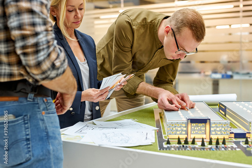 architect engineer is designing the site of building, house blueprint and layout of real estate project while colleagues discuss