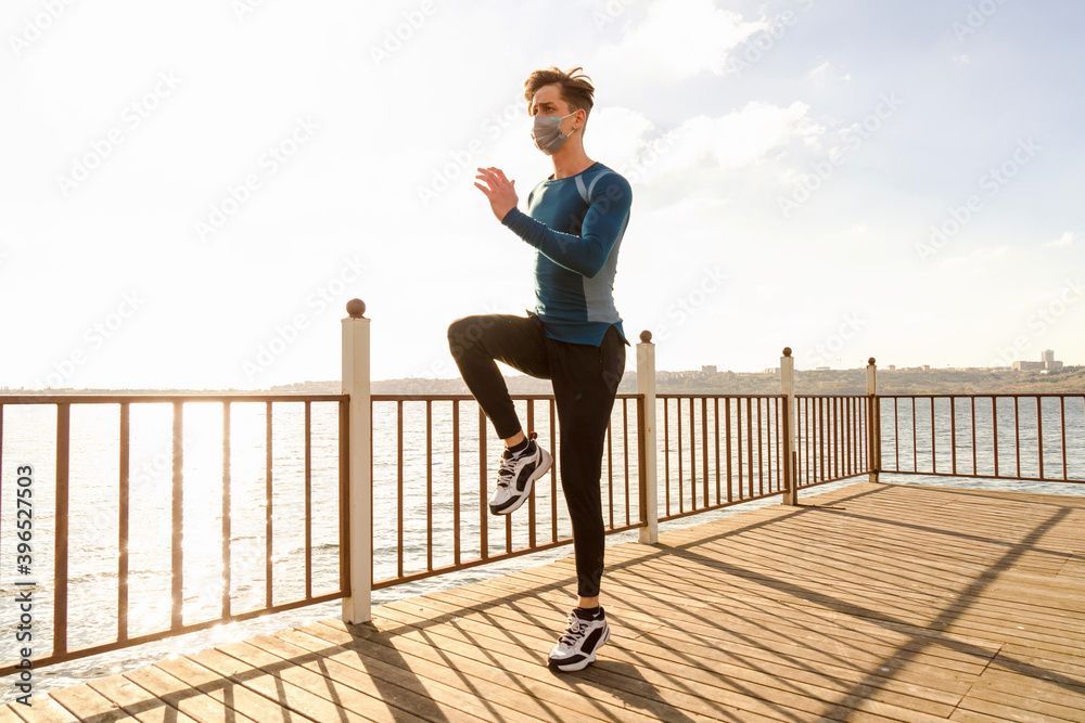 healthy and handsome young male model running on the beach. The man wearing a mask is running by the sea in sportswear. Healthy man who does sports outside with his mask due to corona virus measures. healthy and handsome young male model running on the beach. The man wearing a mask is running by the sea in sportswear. Healthy man who does sports outside with his mask due to corona virus measures.