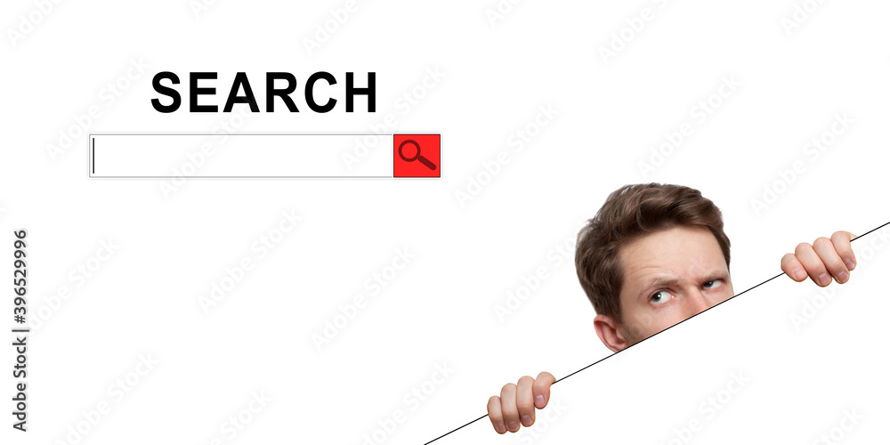 Young man with surprised eyes peeking out from behind billboard on inscription «search Young man with surprised eyes peeking out from behind billboard on inscription «search
