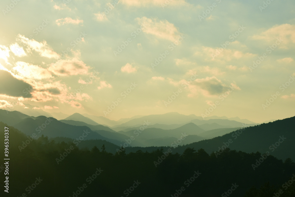 Wolkenstimmung über Bergland mit weichem Lichtfluss über Hügel und Berge im Abendrot	

