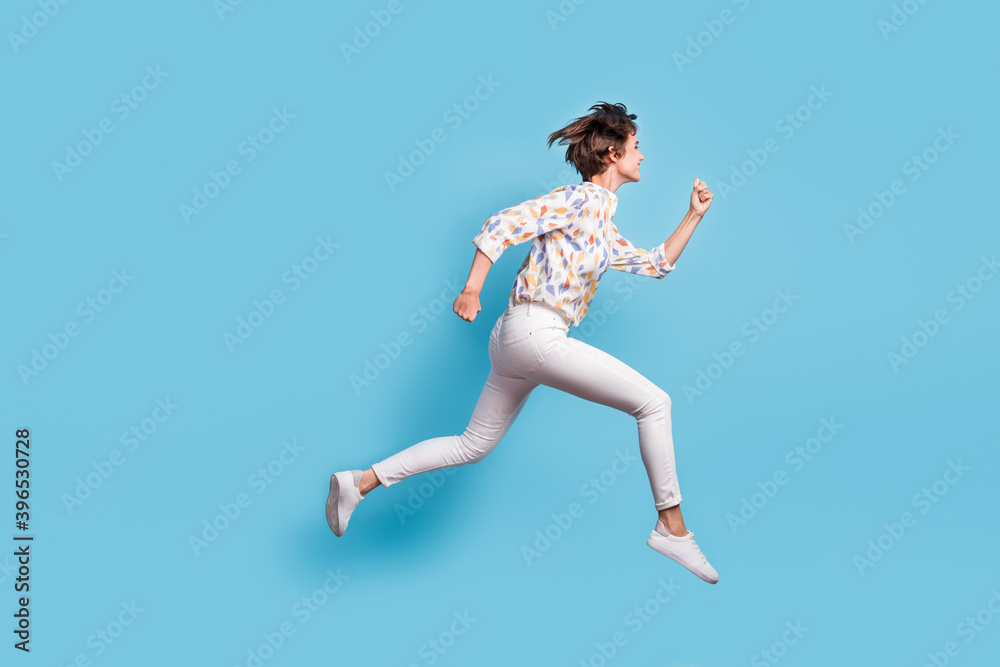 Full body profile side photo of young active girl happy hurry run jump sale look empty space isolated over blue color background Full body profile side photo of young active girl happy hurry run jump sale look empty space isolated over blue color background